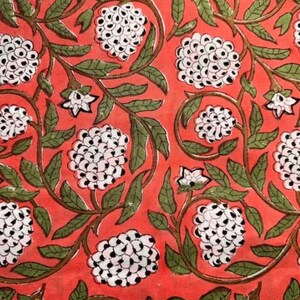 Puede incluir: Una tela roja con un patr&oacute;n repetitivo de flores blancas con centros negros. Las flores est&aacute;n dispuestas en vides verdes.