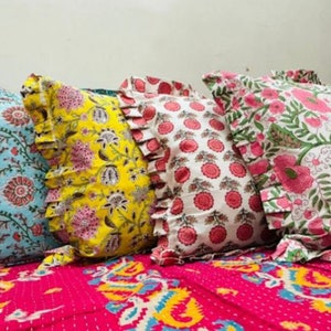 Puede incluir: Cuatro almohadas decorativas con estampados florales. Las almohadas est&aacute;n dispuestas en fila sobre una colcha estampada en rosa y amarillo. Las almohadas tienen bordes con volantes y est&aacute;n hechas de tela de algod&oacute;n. Los estampados incluyen flores rosas y verdes sobre fondo blanco, flores rosas y blancas sobre fondo blanco, flores amarillas y rosas sobre fondo amarillo y flores azules y rosas sobre fondo azul.