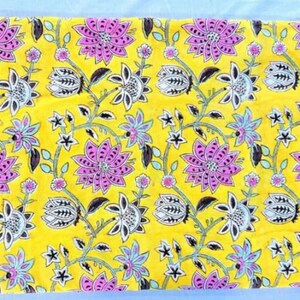 Puede incluir: Tela amarilla con estampado floral con flores rosas y negras sobre fondo amarillo.