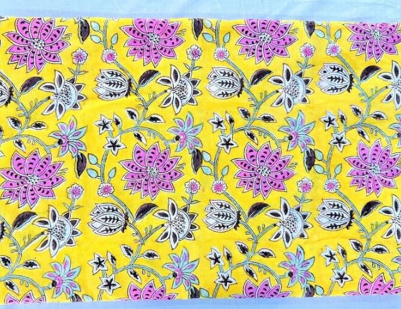 Puede incluir: Tela amarilla con estampado floral con flores rosas y negras sobre fondo amarillo.