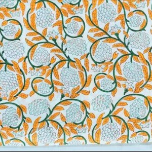 Puede incluir: Tela blanca con un patr&oacute;n repetido de dise&ntilde;os florales azules y blancos con hojas naranjas. La tela tiene un aspecto vintage.