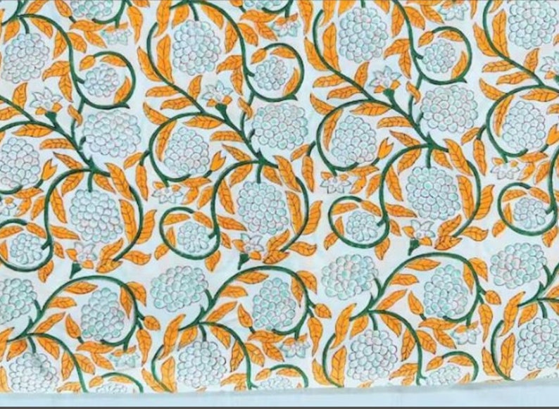 Puede incluir: Tela blanca con un patr&oacute;n repetido de dise&ntilde;os florales azules y blancos con hojas naranjas. La tela tiene un aspecto vintage.