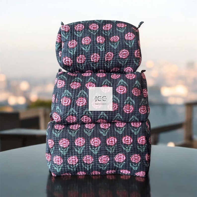 May include: Three black quilted makeup bags with a pink floral pattern. The middle bag has a white label with the text "JCC Home & Co."