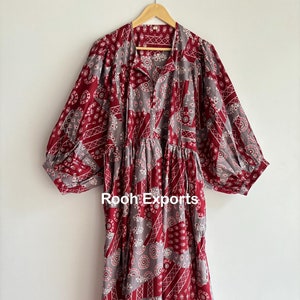 Puede incluir: Un vestido largo de estampado rojo y gris con cuello en V y mangas abullonadas. El vestido tiene una falda fruncida y está hecho de una tela ligera. "Rooh Exports" está impreso en la parte delantera del vestido.