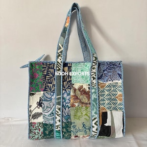 May include: A patchwork tote bag with a variety of floral and geometric patterns in shades of blue, green, and brown. The bag has sturdy handles and a blue trim. The text "ROOH EXPORTS" is visible on the bag.