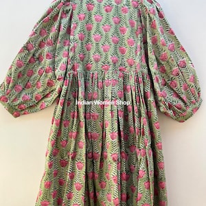 Puede incluir: Un vestido de estampado floral verde y rosa con cintura fruncida y mangas largas. El vestido tiene un escote en V y un corte holgado. El texto "Indian Women Shop" es visible en el vestido.