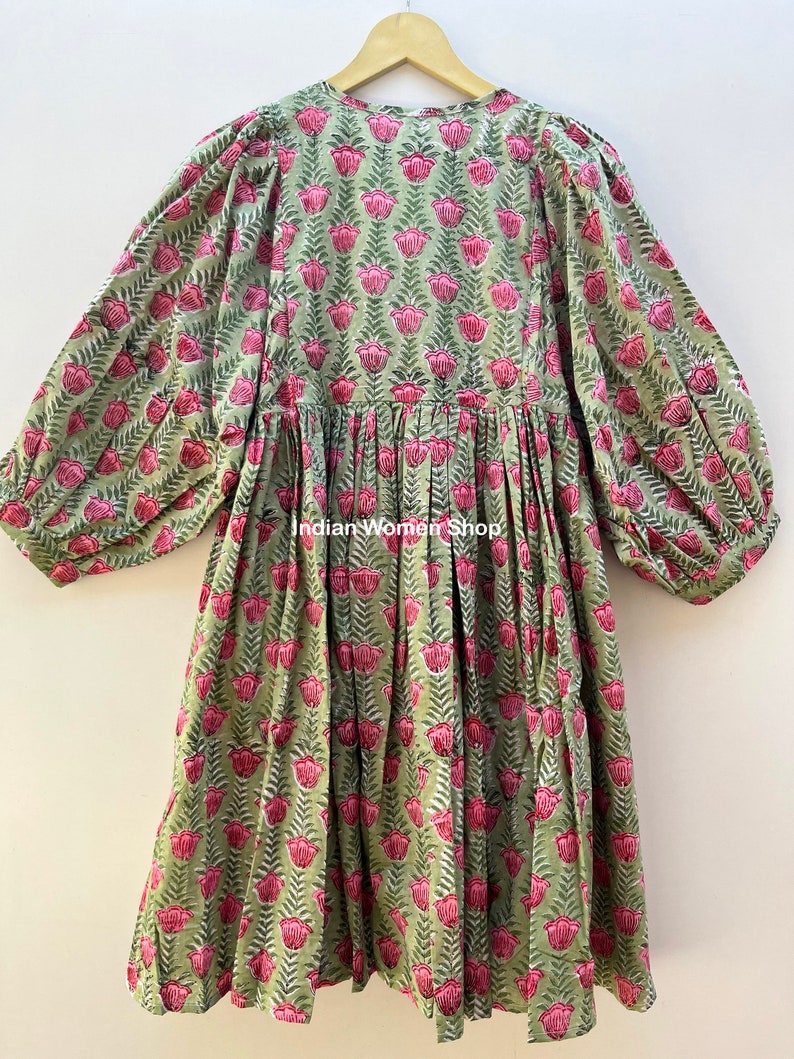 Puede incluir: Un vestido de estampado floral verde y rosa con cintura fruncida y mangas largas. El vestido tiene un escote en V y un corte holgado. El texto "Indian Women Shop" es visible en el vestido.