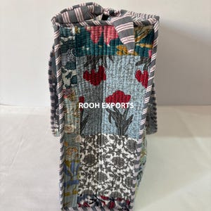 May include: A patchwork tote bag with a variety of floral and geometric patterns in shades of blue, red, and gray. The bag has a striped handle and trim, and the text "ROOH EXPORTS" is visible.