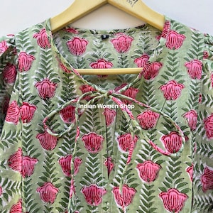 Puede incluir: Un vestido de estampado floral verde y rosa con un lazo en el escote. El vestido tiene una peque&ntilde;a etiqueta de talla en el escote. El texto "Indian Women Shop" es visible en el vestido.