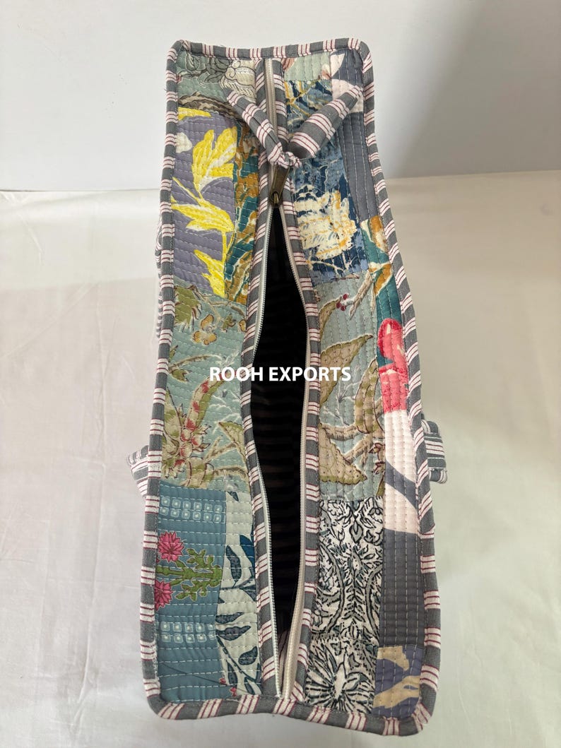 May include: A quilted tote bag with a patchwork design featuring floral and botanical patterns in shades of blue, gray, yellow, and pink. The bag has a gray zipper and striped handles. The text "ROOH EXPORTS" is visible.