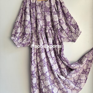 May include: A long, purple cotton dress with a white floral print. The dress has a gathered skirt and puffed sleeves.