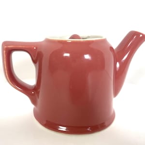 Puede incluir: Una tetera de cerámica roja con interior blanco y un diseño sencillo.