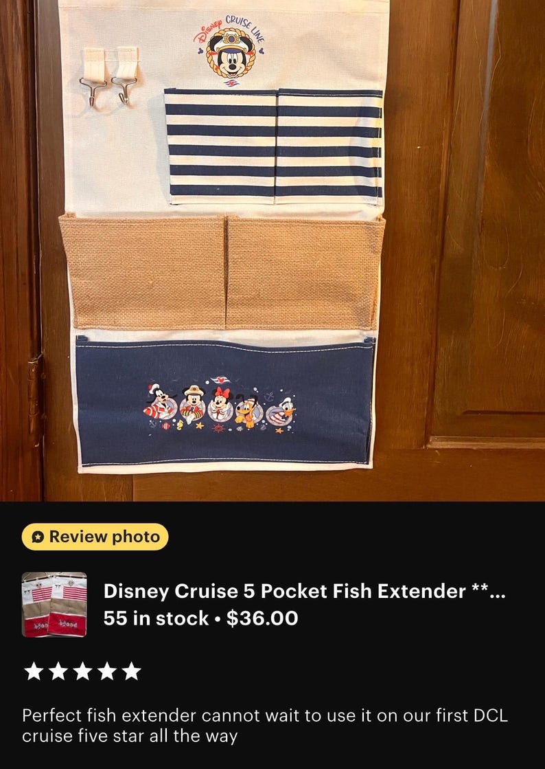 May include: A multi-pocket organizer with a Disney Cruise Line theme. The top section is off-white with two small hooks. Below is a section with navy blue and white stripes. The bottom section is navy blue with embroidered Disney characters.