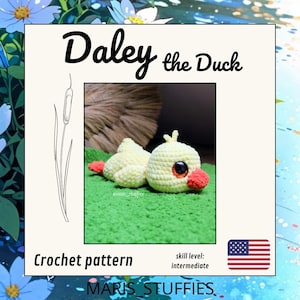 Puede incluir: Un pato amarillo tejido a ganchillo llamado "Daley the Duck" con patas y pico naranjas, tumbado sobre tela verde. La imagen incluye el texto "Crochet pattern" y "skill level: intermediate". La bandera americana está en la esquina inferior derecha.