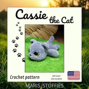 Op de afbeelding: Een gehaakt grijs kattenknuffel genaamd "Cassie the Cat" op een groene ondergrond. De afbeelding bevat de tekst "Crochet pattern" en "skill level: intermediate". De Amerikaanse vlag staat rechtsonder. Zwarte pootafdrukken staan links.