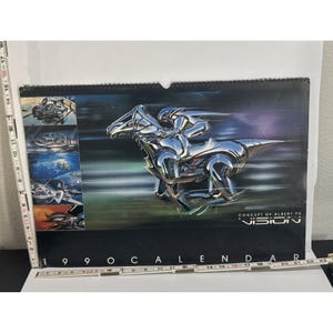 May include: A 1990 calendar featuring a futuristic chrome horse and rider design. The calendar has a black background with the text "VISION" and "CONCEPT OF ALBERT YU". Additional images of futuristic vehicles are on the left side.
