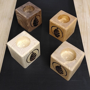 Può includere: Quattro portacandele in legno con un design a foglia. I portacandele sono in due diverse tonalità di legno, uno è marrone scuro e l'altro è marrone chiaro.