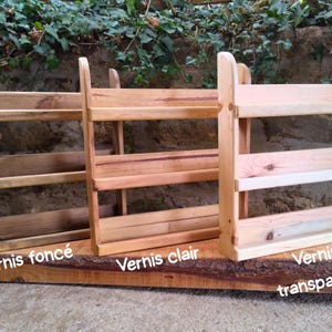 May include: Three wooden spice racks with varying finishes: dark, light, and transparent. Each rack has two shelves and a backboard. The racks are mounted on a natural wood base. Text on the base reads "Varnish" followed by a color description.