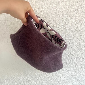 Könnte beinhalten: Ein lilafarbener Fleece-Halswärmer mit einem weißen Blumenmuster als Futter.