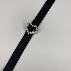 May include: A black ribbon with a silver heart-shaped buckle adorned with clear rhinestones.