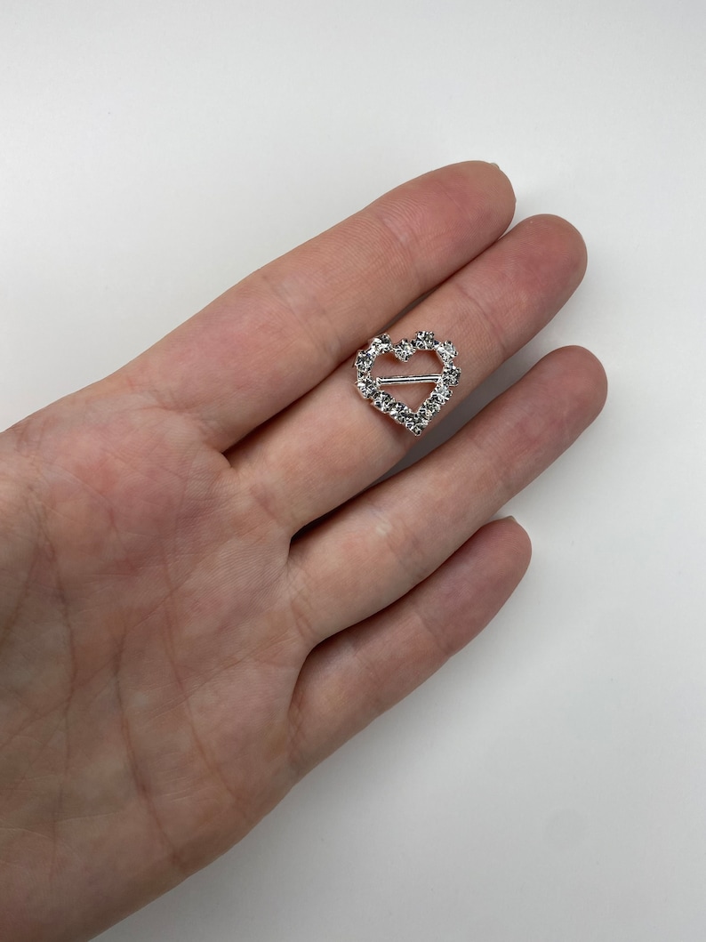 May include: A silver heart-shaped buckle with clear rhinestones.