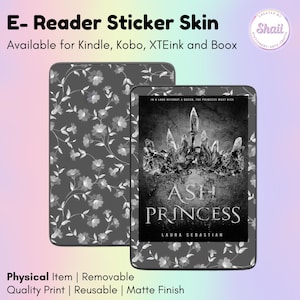 May include: A matte finish e-reader sticker skin featuring a dark gray background with a white floral pattern. One version displays the book cover for Ash Princess by Laura Sebastian, showing a crown illustration and the text Ash Princess.