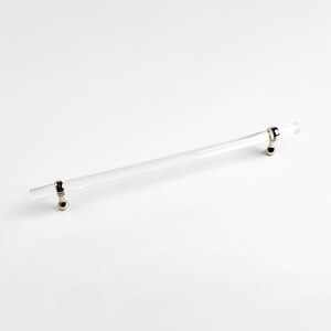 May include: A clear acrylic cabinet pull with polished nickel end caps. The pull is approximately 10 inches long.