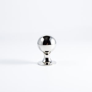 May include: A polished chrome knob with a round top and a circular base.
