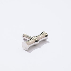 May include: A silver-toned, T-shaped cabinet pull with a bamboo-inspired design. The pull has a smooth, polished finish.