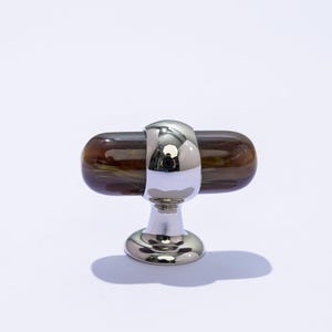 May include: A brown and gold cabinet knob with a silver base and a round, decorative top.