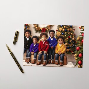 May include: Five young boys wearing colorful sweaters and jeans pose in front of a Christmas tree. They are all smiling and looking at the camera. The tree is decorated with ornaments and lights.