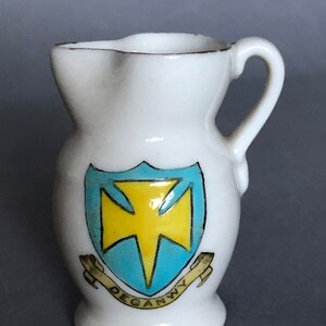 May include: A white ceramic pitcher with a gold rim and a blue and yellow crest with the text "Deganwy" on a white background.