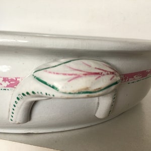 Peut inclure: Plat de service en céramique blanche avec un motif de feuille rose et verte sur la poignée. Le plat a une bande rose autour du bord. La poignée est en forme de feuille avec des veines roses et une bordure verte. Une pièce vintage.