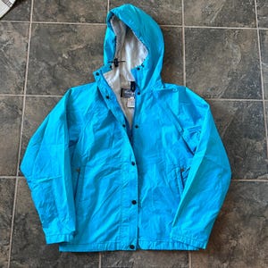 May include: A bright blue hooded jacket with a snap closure and a black label that says "Wrangler" on the front.