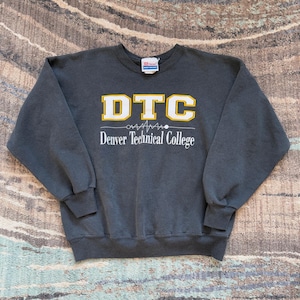 May include: Dark gray DTC Denver Technical College sweatshirt. The sweatshirt has a crew neck and long sleeves. The DTC logo is in yellow with a white outline, and the words "Denver Technical College" are below the logo.