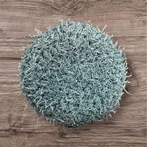 May include: A round, handmade, light blue crocheted item with a textured, fuzzy appearance. The item is made of a soft, looped yarn, and the edges have a fringe-like detail. The item is likely a decorative piece or a functional item, such as a washcloth.