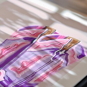 May include: A close-up of a purple and pink patterned fabric with a white background. The fabric has a geometric design with a swirling pattern.