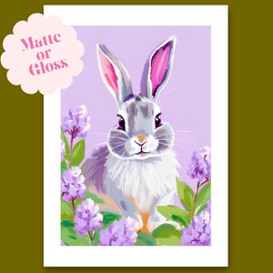 K&ouml;nnte beinhalten: Ein wei&szlig;es Kaninchen mit rosa Ohren sitzt in einem Feld mit lila Blumen. Das Kaninchen hat ein weiches, flauschiges Fell und einen s&uuml;&szlig;en Ausdruck. Der Hintergrund ist helllila.