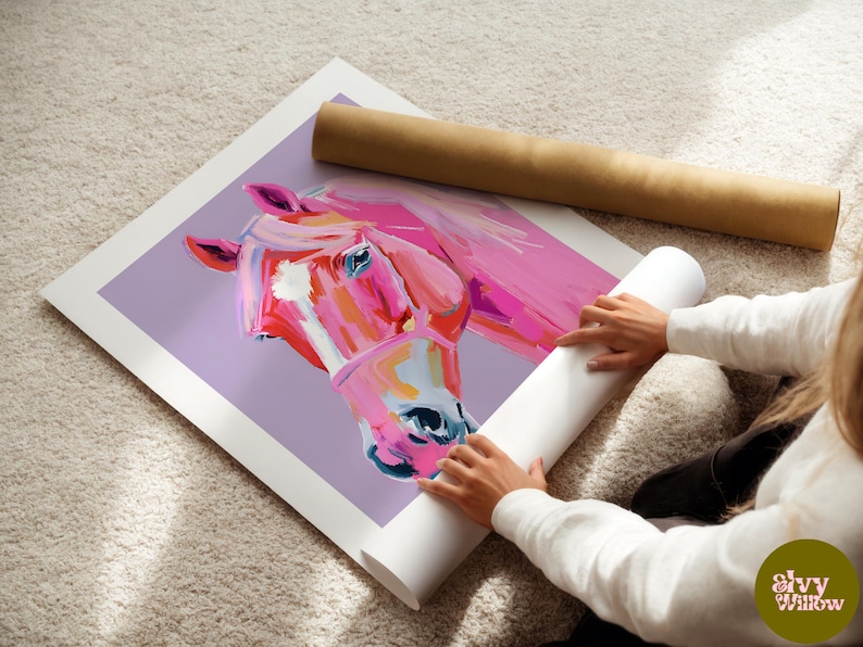 Peut inclure: Un gros plan d'une peinture de cheval rose sur fond violet. La t&ecirc;te du cheval est tourn&eacute;e de c&ocirc;t&eacute; et son &oelig;il est visible. La peinture est dans un format de poster enroul&eacute;.