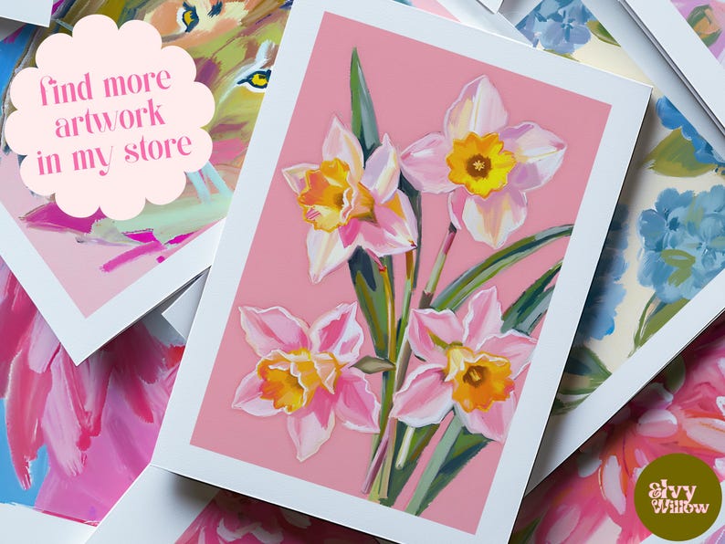 Peut inclure: Une carte de v&oelig;ux rose avec une bordure blanche pr&eacute;sente une peinture de trois jonquilles roses et jaunes sur un fond rose. Le texte "find more artwork in my store" est &eacute;crit dans un nuage blanc en haut &agrave; gauche.