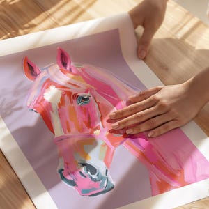 Peut inclure: Une peinture de t&ecirc;te de cheval rose et orange sur fond violet. L'&oelig;il du cheval est visible et la peinture a un aspect stylis&eacute; et abstrait.