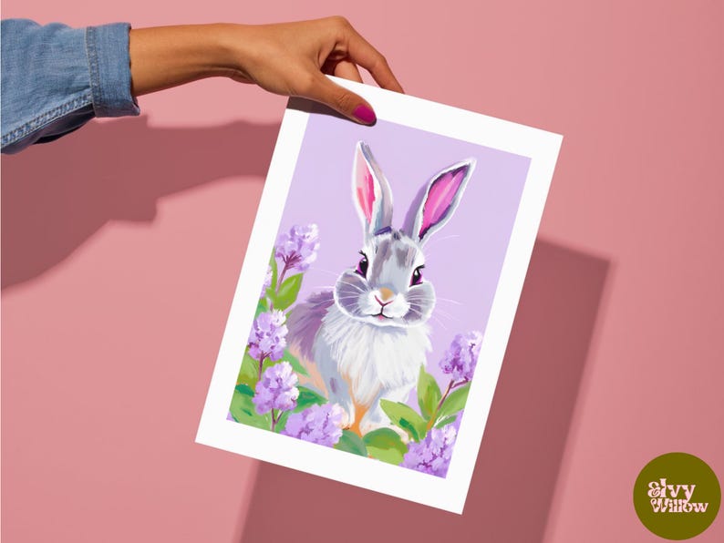 K&ouml;nnte beinhalten: Eine digitale Illustration eines grauen Kaninchens mit rosa Ohren, umgeben von lila Blumen auf einem helllila Hintergrund.