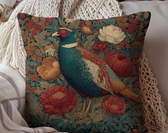 May include: Decorative square pillow featuring a detailed illustration of a pheasant amidst a floral pattern. The bird has teal, red, and white plumage, set against a backdrop of red, orange, and cream-colored flowers and green foliage.