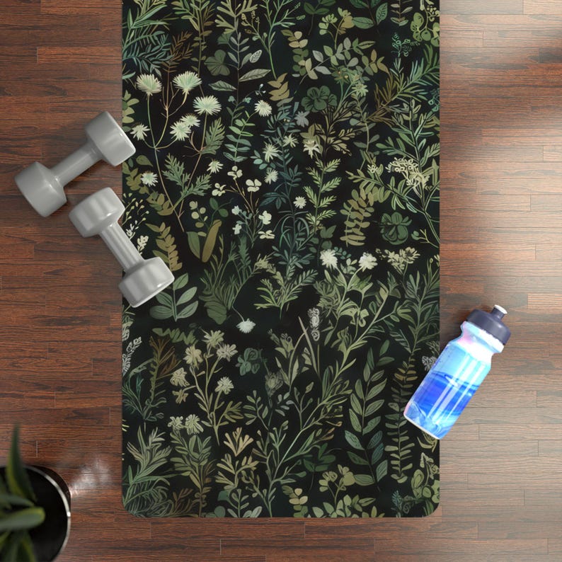 May include: A black yoga mat with a floral pattern featuring green leaves and white flowers. The mat is on a wooden floor with a water bottle and weights.