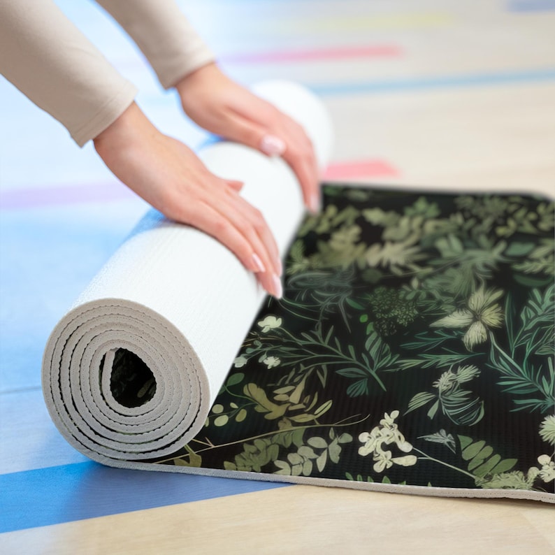 May include: A rolled up yoga mat with a black background and a green and white floral pattern.