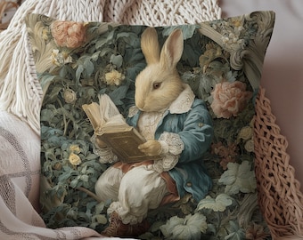 May include: Decorative square pillow featuring a rabbit in a blue jacket reading a book. The rabbit is surrounded by a floral design with roses and foliage. The pillow has a vintage, storybook aesthetic.