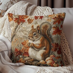 May include: A throw pillow with a brown squirrel sitting in a forest scene with red and orange leaves. The squirrel is holding a nut in its paws.