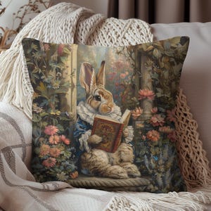 May include: Decorative throw pillow featuring a vintage illustration of a rabbit reading a book. The rabbit is dressed in a blue coat and white ruffled collar, surrounded by flowers. The pillow has a floral and garden theme.
