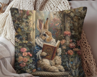 May include: Decorative throw pillow featuring a vintage illustration of a rabbit reading a book. The rabbit is dressed in a blue coat and white ruffled collar, surrounded by flowers. The pillow has a floral and garden theme.
