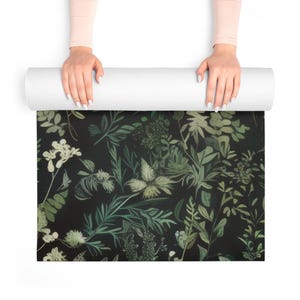 May include: A rolled-up yoga mat with a dark green and white floral pattern. The mat is unfurling to reveal the design.